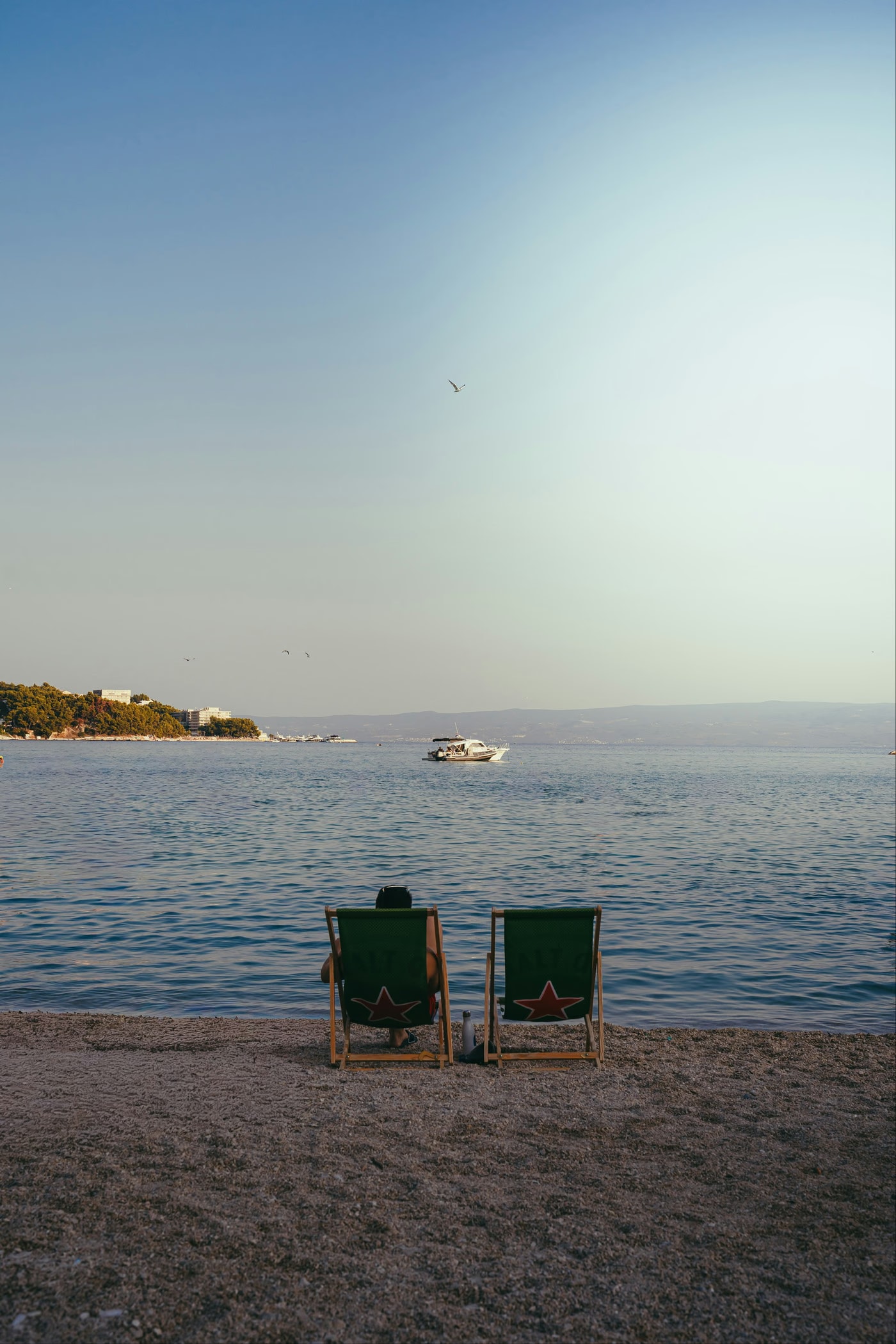 Two deckchairs on a beach facing the sea