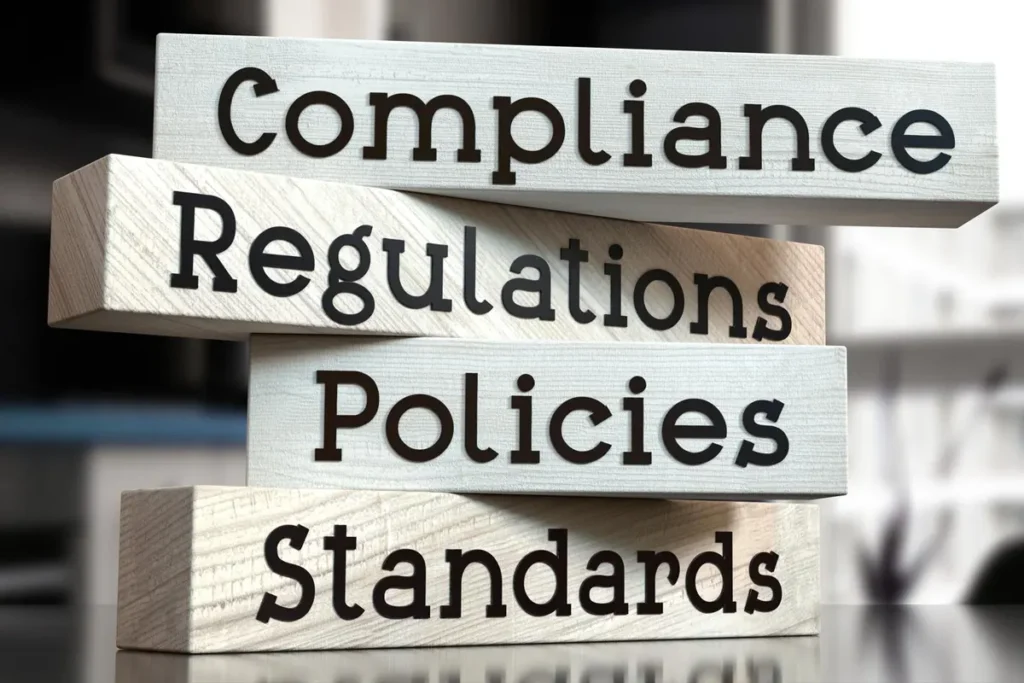 Stacked blocks labeled compliance, regulations, policies, and standards representing legal and regulatory frameworks